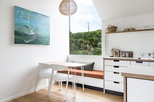 a kitchen with a table and chairs and a window at Wainui Landing Apartment 2 in Raglan