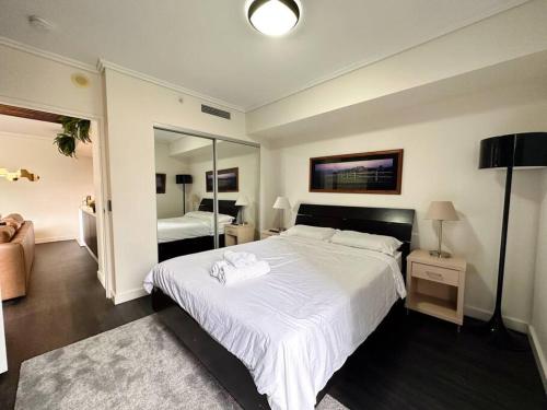 1 dormitorio con 1 cama blanca grande y espejo en S&P - Festival, en Brisbane