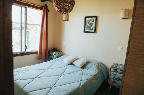 1 dormitorio con 1 cama con edredón azul y ventana en Don Tito, en Aguas Dulces
