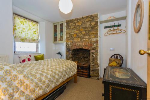 a bedroom with a bed and a stone fireplace at APPLEDORE GANNETS NEST 3 Bedrooms in Appledore