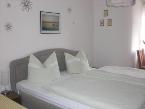 um quarto com 2 camas com lençóis brancos e almofadas em Pension Villa Sophia em Sassnitz