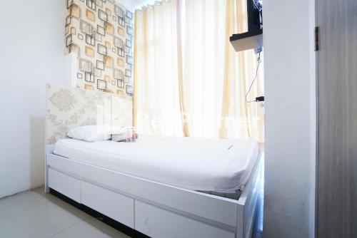 una camera con un letto bianco e una finestra di Eascot Hotel Mitra RedDoorz a Giacarta