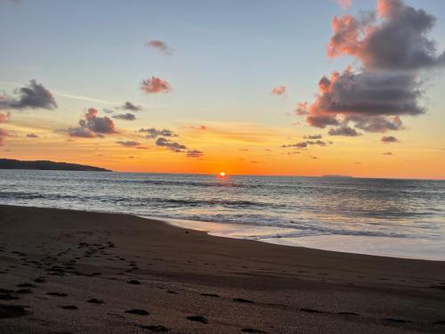 a sunset on a beach with the ocean at Ceiba lodge in Drake