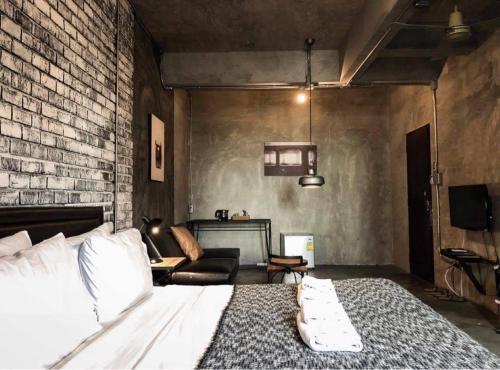 ein Schlafzimmer mit einem Bett und einer Ziegelwand in der Unterkunft Samantan Hotel at Nimman in Chiang Mai