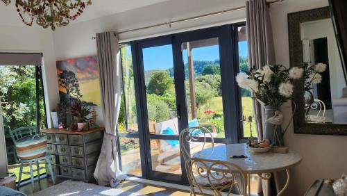 a living room with a table and a glass door at Boutique Art Retreat in Upper Hutt