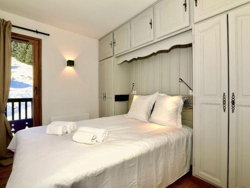 une chambre avec un grand lit blanc avec deux serviettes dessus dans l'établissement Appartement rénové 42m² - 4 pers - Courchevel 1550, Sud, skis aux pieds, proche centre, parking inclus - FR-1-631-121, à Courchevel