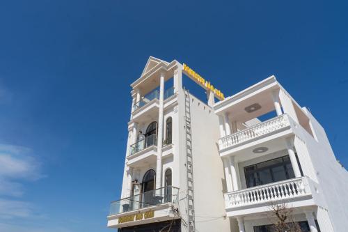 a white building with balconies and a blue sky at Homestay Bảo Châu - Nhơn Lý Quy Nhơn in Quy Nhon