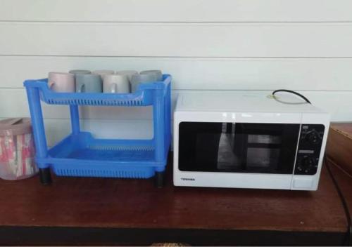 a white microwave sitting on a table next to cups at Farm House kohyaoyai in Ko Yao Yai