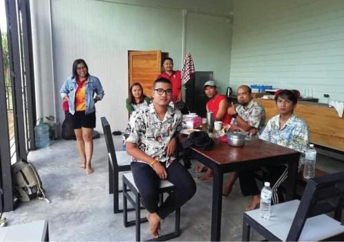 eine Gruppe von Personen, die an einem Tisch in einem Zimmer sitzen in der Unterkunft Farm House kohyaoyai in Ko Yao Yai