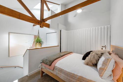 a bedroom with a bed with white walls and wooden beams at Self Contained Loft Apartment in CBD in Devonport