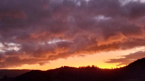 a cloudy sky at sunset over a mountain at Boutique Art Retreat in Upper Hutt