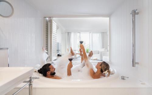 two people are in a bath tub with bubbles at Bannisters by the Sea Mollymook in Mollymook