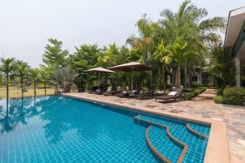 a swimming pool with chairs and umbrellas next to a building at Countryside Villa, 2 Bedroom Villa, Infinity Pool and maid service in Chiang Mai