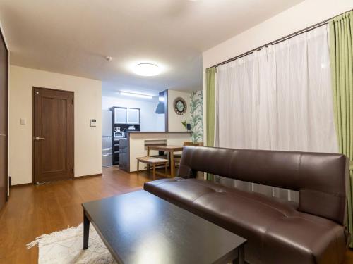 Una sala de estar con un sofá de cuero y una mesa. en Ocean Front Maezato, en Ishigaki Island