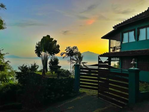 a house with a fence in front of a sunset at Villa Borobudur Resort in Borobudur
