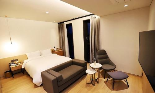 um quarto de hotel com uma cama e um sofá em Gangneung Grey Hotel em Gangneung