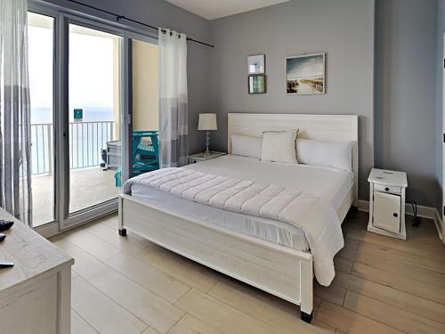 a bedroom with a large white bed and a balcony at Ocean Villa 2106 in Panama City Beach