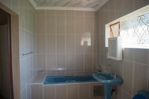 baño con lavabo azul y ventana en Haithoms B&B Tlokweng-Gaborone en Tlokweng