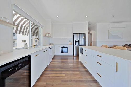 uma grande cozinha branca com balcões brancos e armários brancos em The Lookout em Bargara