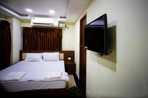 a bedroom with a bed and a flat screen tv at Hotel Sea Land in Kanyakumari