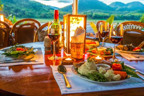 a table with a plate of food and glasses of wine at Mekong Riverview Hotel in Luang Prabang