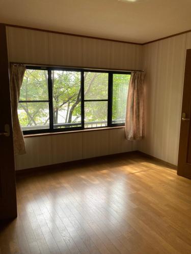an empty room with two large windows and a wooden floor at Breath in Earth BandB民泊 戸隠TOGAKUSHI in Nagano