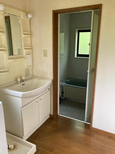 a bathroom with a tub and a sink and a mirror at Breath in Earth in Nagano