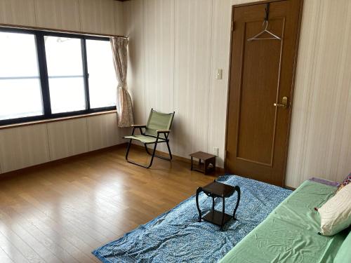 1 dormitorio con 1 cama, 1 silla y 1 ventana en Breath in Earth, en Nagano