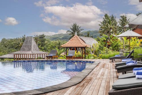 een zwembad in een resort met stoelen en een prieel bij The Kleep Jungle Resort in Nusa Penida