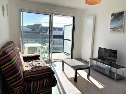 un salon avec un canapé, une table et une télévision dans l'établissement Charmant T2 à Quiberon, balcon sud, parking, à 300m des commerces et plage - FR-1-478-162, à Quiberon