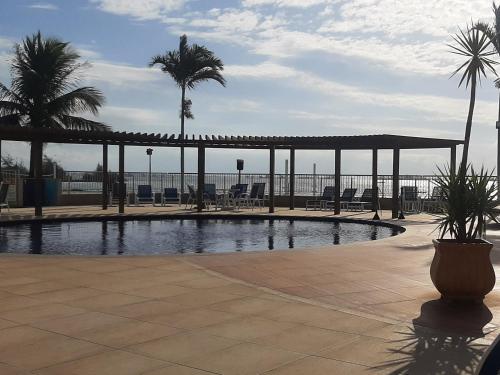 una piscina con un pabellón, palmeras y el océano en Golden Lake - Arraial do Cabo, en Arraial do Cabo