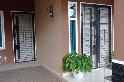 uma casa com duas portas e uma planta em frente em Cheerfull residential home - Dillair Home Stay em Talang Kelapa