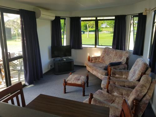 a living room with two couches and a television at Te Puru Holiday Park in Thames