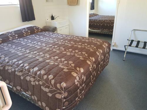 a bedroom with a large bed with a brown comforter at Te Puru Holiday Park in Thames
