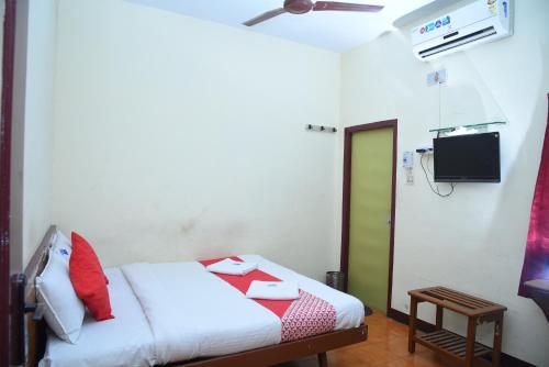 a room with a bed with a green door and a television at Hotel Radhakrishna in Madurai