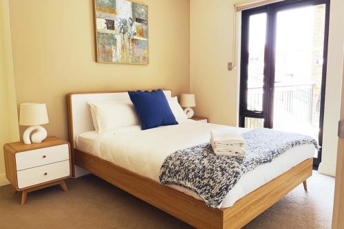 Un dormitorio con una cama con almohadas azules y una ventana en Rooftops On Henrycentre Of West End Cafes en Fremantle
