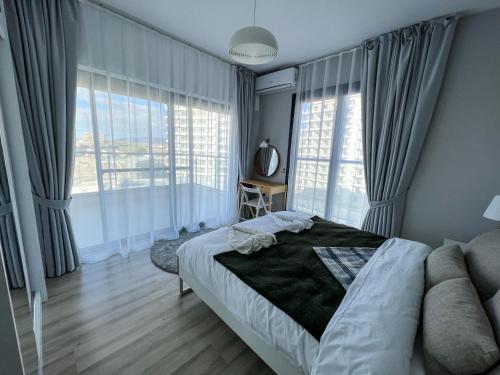 a bedroom with a bed and large windows at Sophia Pool Apartments in Caesar Blue Resort including Breakfast till 4pm, Gym, 5 Swimming Pools, Sauna, Hammam, Kids' club available in Perivolia tou Trikomou