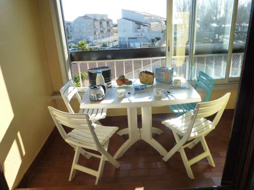 une table blanche et des chaises sur un balcon dans l'établissement Appartement rénové 4 pers. proche plage, calme, parking, animaux acceptés - FR-1-387-131, à Marseillan