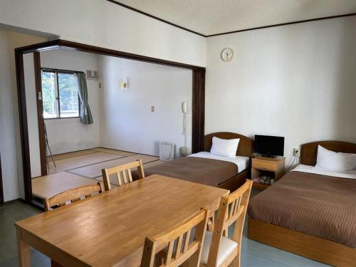 Zimmer mit 2 Betten, einem Holztisch und Stühlen in der Unterkunft On the Beach Lue - Vacation STAY 91567v in Sesoko