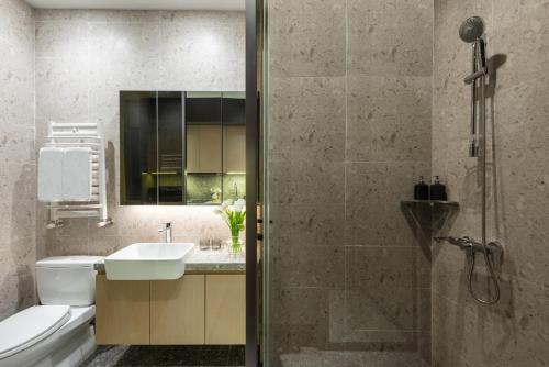 La salle de bains est pourvue d'un lavabo, de toilettes et d'une douche. dans l'établissement base-Beijing Sanlitun Serviced Apartment, à Pékin