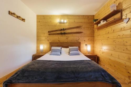 Appt Bec A2 - Happy Rentals في Le Tour: غرفة نوم بسرير كبير وبجدران خشبية