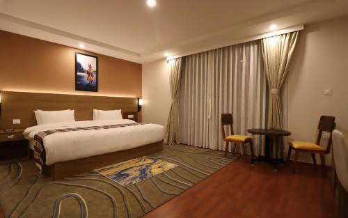 ein Hotelzimmer mit einem Bett, einem Tisch und Stühlen in der Unterkunft Thimphu Deluxe Hotel in Thimphu
