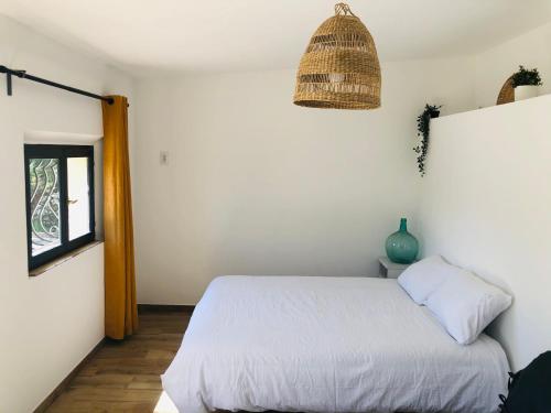 sypialnia z białym łóżkiem i oknem w obiekcie Le Cabanon w mieście Collobrières