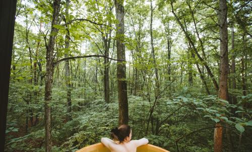a woman walking through a forest with a surfboard at Tatehata House. Private Sauna. Outdoor Bath. in Kita-karuizawa