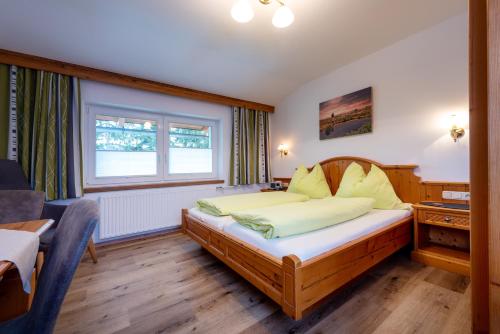a bedroom with a bed with yellow pillows and a window at Energiepension Schwaiger in Leogang