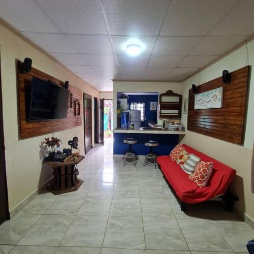 a living room with a red couch and a kitchen at Casa-cabaña Jefe Indio /Playa Cacique in Cacique