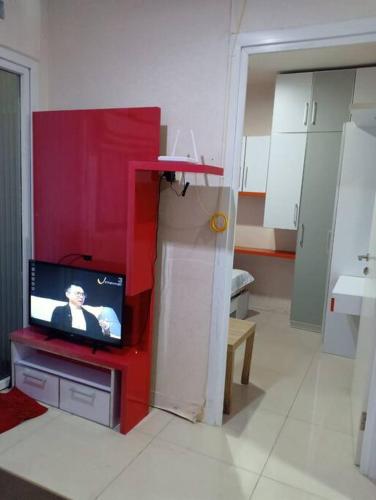 uma sala de estar com uma televisão num armário vermelho em Comfort 2BR green pramuka bougenvile em Jakarta