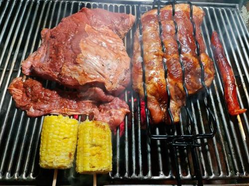 a grill with meat and corn on it at Casa-cabaña Jefe Indio /Playa Cacique in Cacique