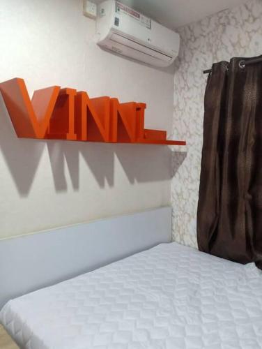 um quarto com uma cama e um sinal laranja na parede em Comfort 2BR green pramuka bougenvile em Jakarta