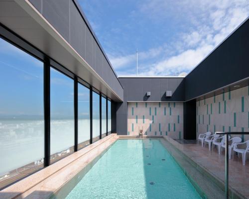 a swimming pool in a building with a view of the ocean at Candeo Hotel Utsunomiya in Utsunomiya